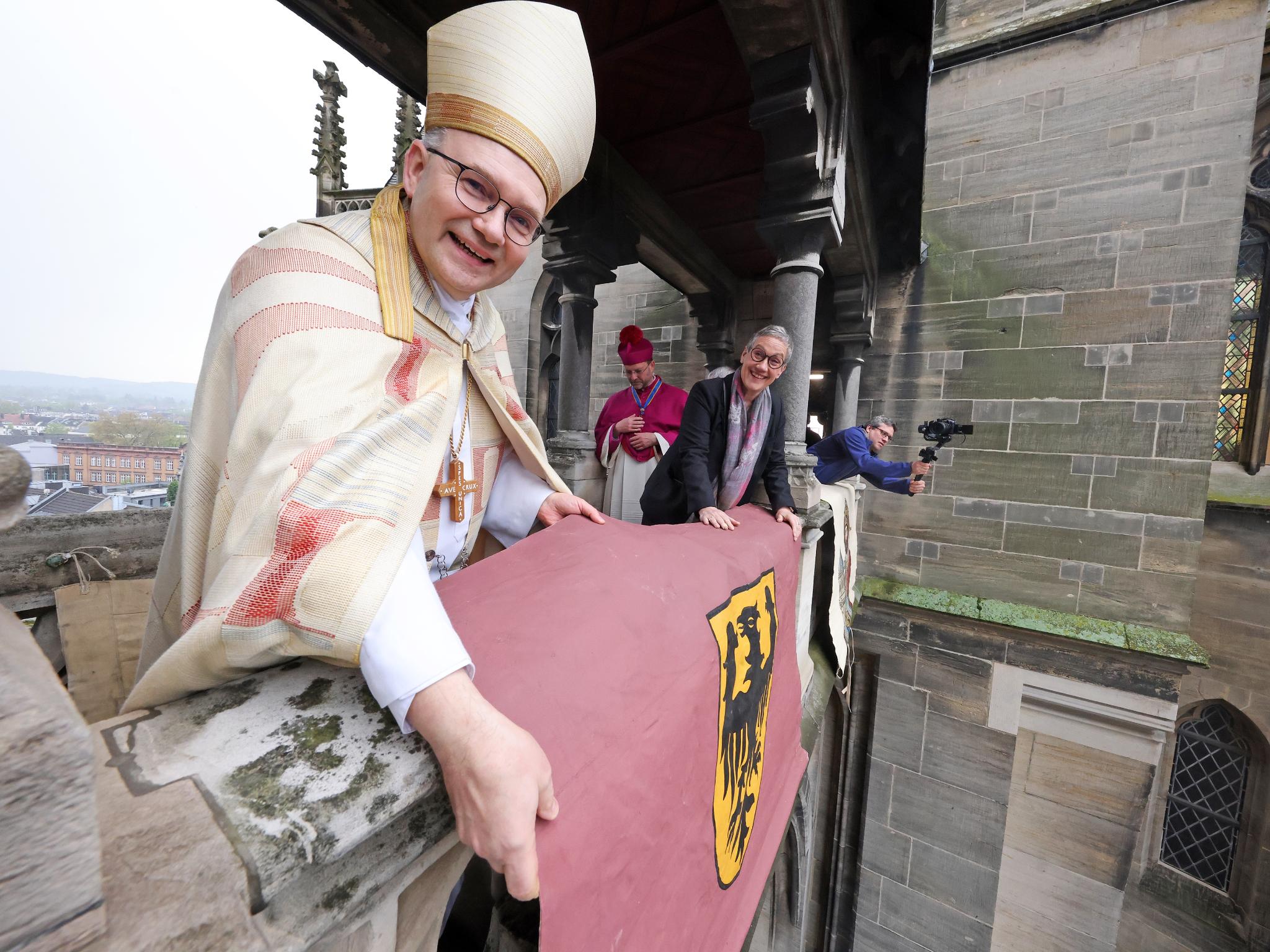 Mit einer feierlichen Vesper unter Beteiligung von Domchor und Domorchester und dem Auslegen der Schmucktücher ist die „heiße Phase“ der Heiligtumsfahrt 2023 eröffnet worden. Dompropst und Wallfahrtsleiter Rolf-Peter Cremer sprach die offizielle Einladung zur Heiligtumsfahrt aus. „Es sind noch 39 Tage, der Countdown läuft“, sagte er mit Nachdruck. Nach der Vesper wurden auf dem Balkon des Domes und der Galerie die Schmucktücher ausgelegt. „Diese Schmucktücher stammen aus dem Anfang des 19. Jahrhunderts, aus einer Zeit, als man keine Plakate hatte, aber Zeichen brauchte, die weithin sichtbar das Besondere, die Heiligtumsfahrt, ankündigen konnten“, berichtet Cremer.